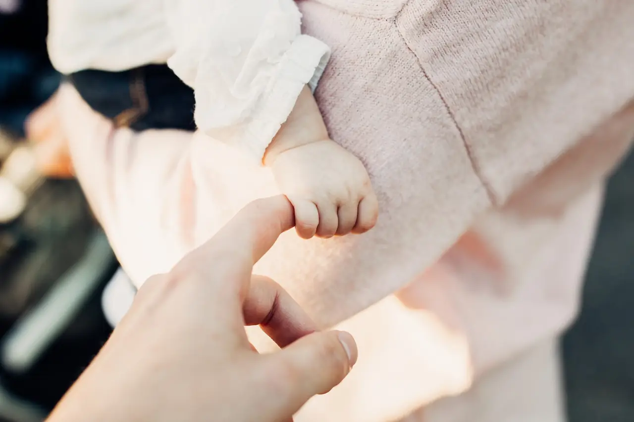 Ein Baby hält den Finger eines Erwachsenen fest