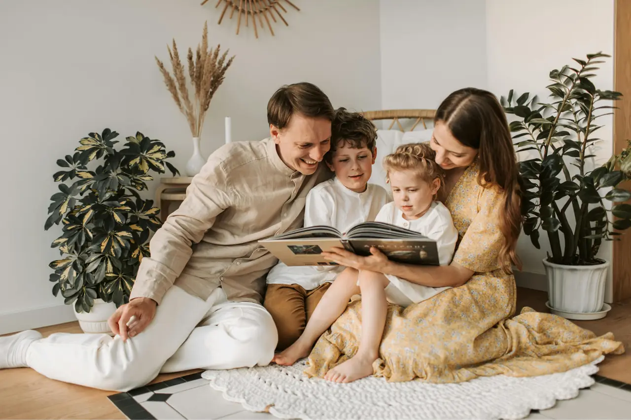 Eine Familie sitzt gemeinsam auf dem Boden und schaut sich ein Buch an