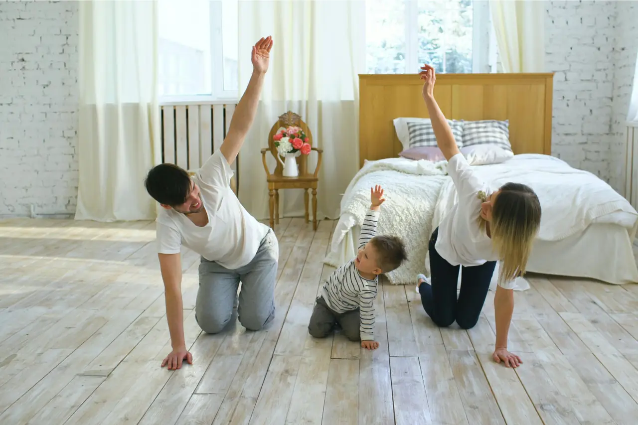 Eine Familie bewegt sich gemeinsam auf dem Boden im Wohnzimmer