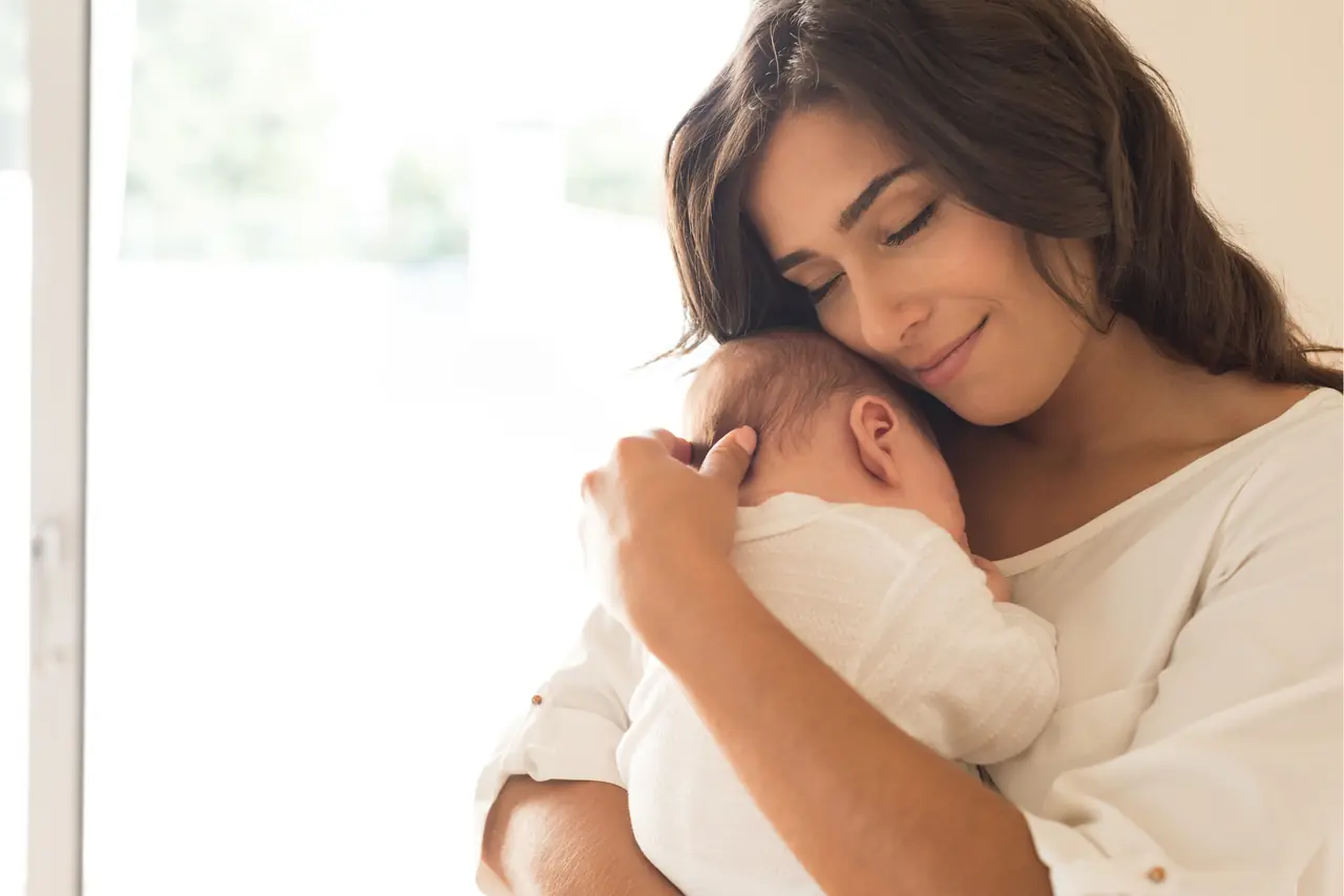 Eine lächelnde Mutter hält ihr Baby sanft im Arm