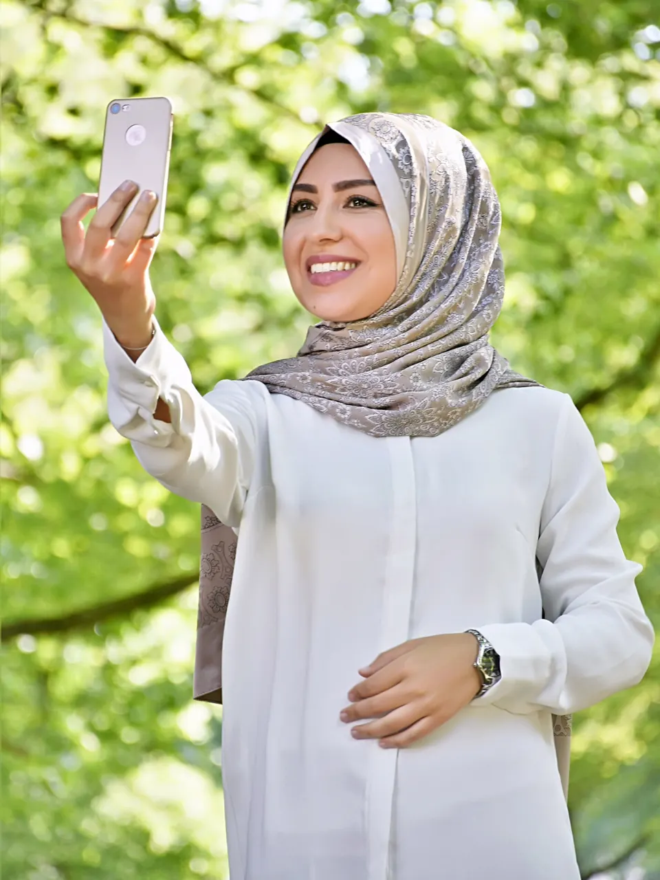 Özlem Tekdemir hält lächelnd ein Smartphone in der Hand